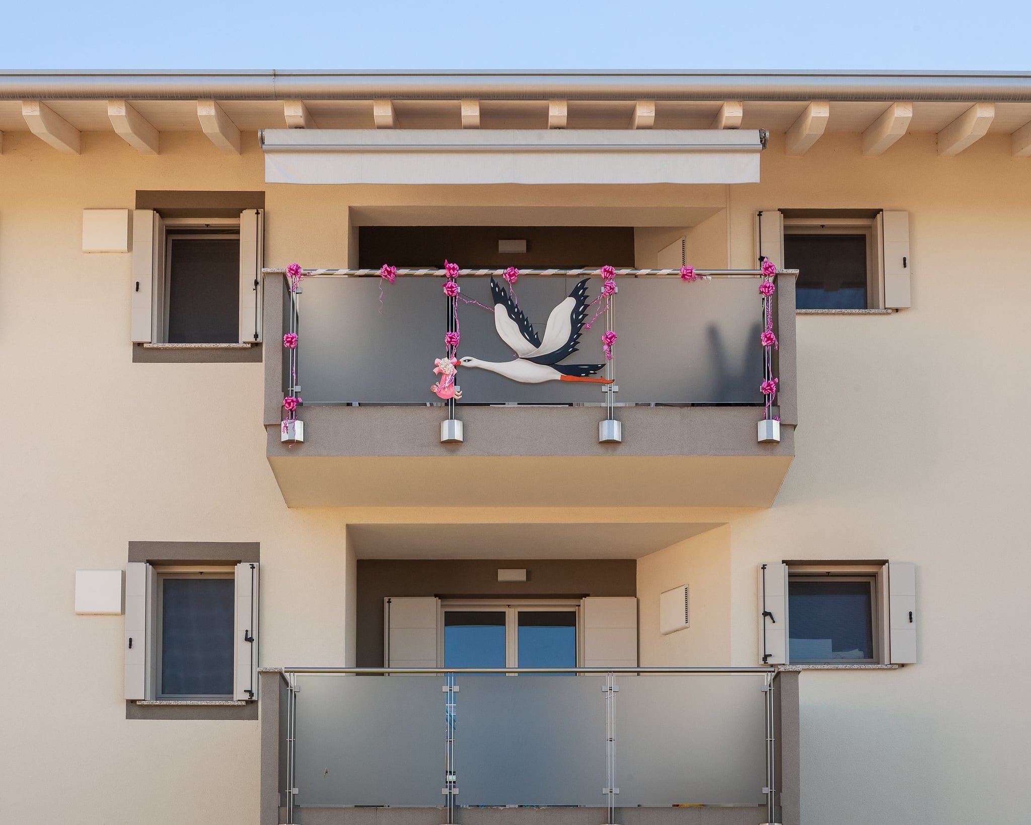 Balcone di una casa decorato con una cicogna e fiocchi rosa per festeggiare l'arrivo di una bimba, prima del battesimo