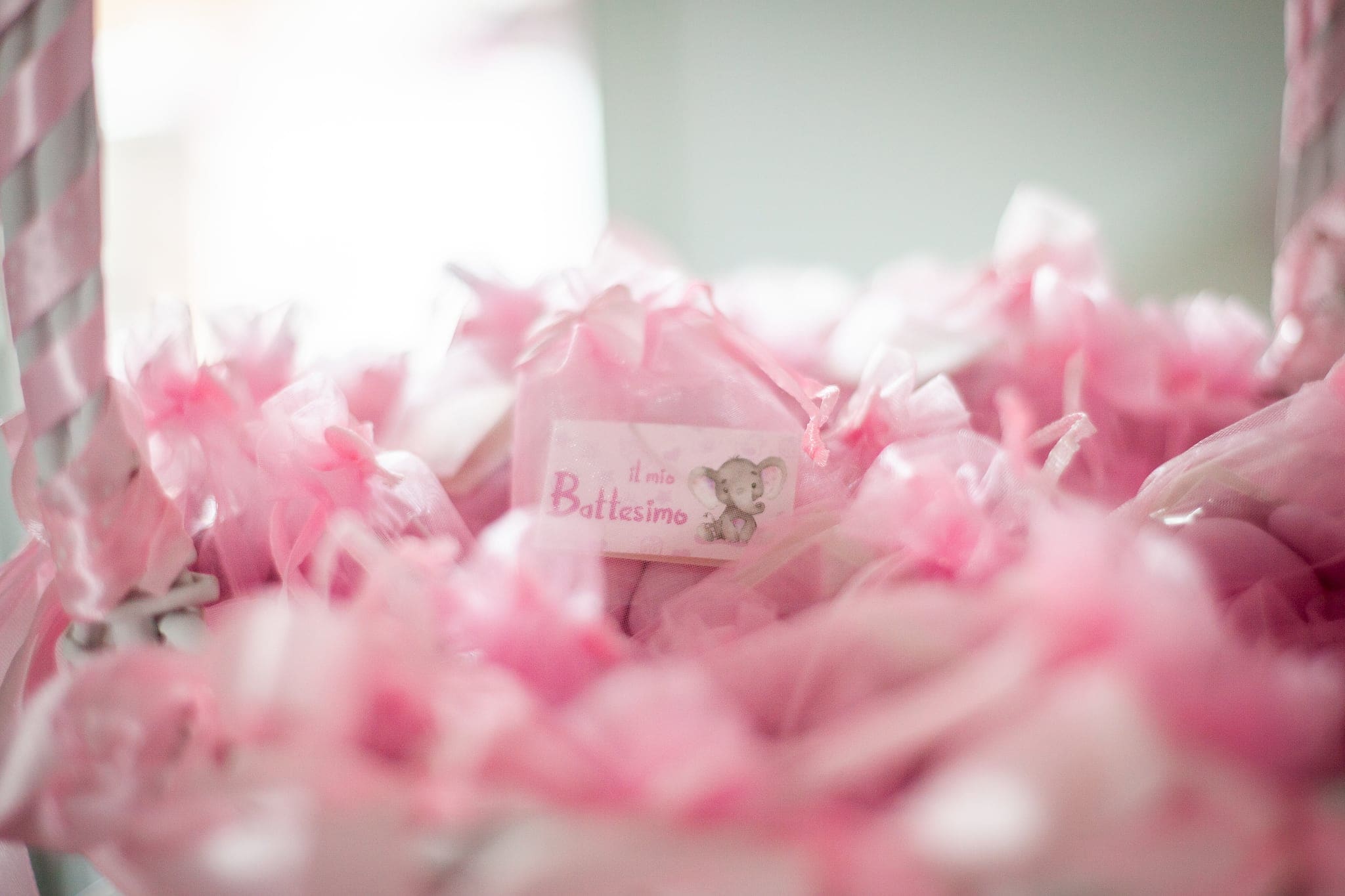 Cesto pieno di sacchettini di tulle rosa con un cartoncino con elefantino e la scritta Battesimo