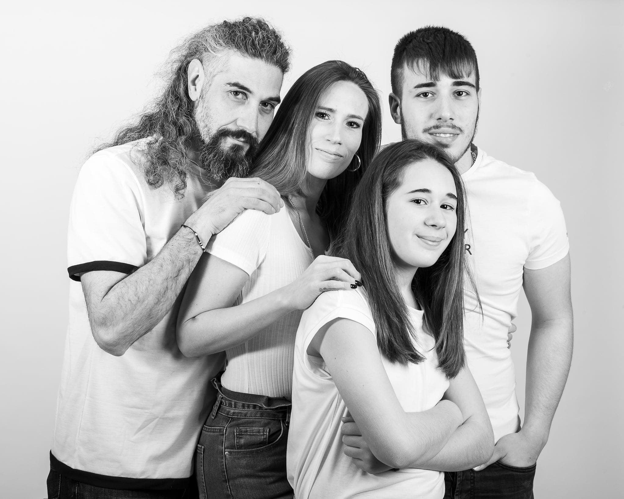 Ritratto di famiglia in bianco e nero con un papà dai capelli lunghi, una mamma e due figli ragazzi che sorridono
