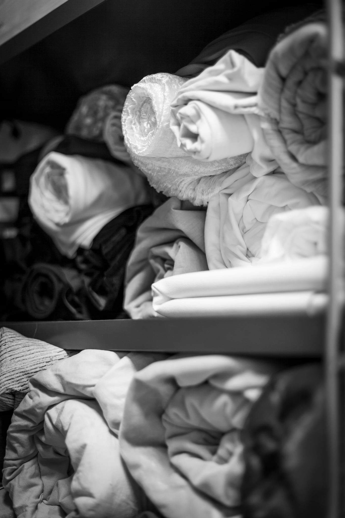 Rotoli di tessuti e coperte bianche riposti in un armadio dello studio, usati come fondali per i servizi