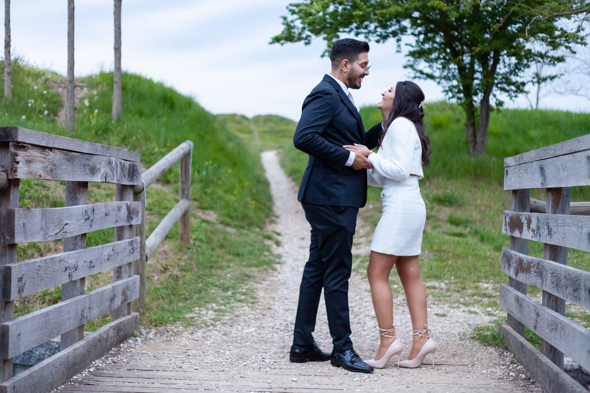 Sposi che si guardano sorridendo su un sentiero di ghiaia con staccionata in legno e prato verde, matrimonio a Palmanova